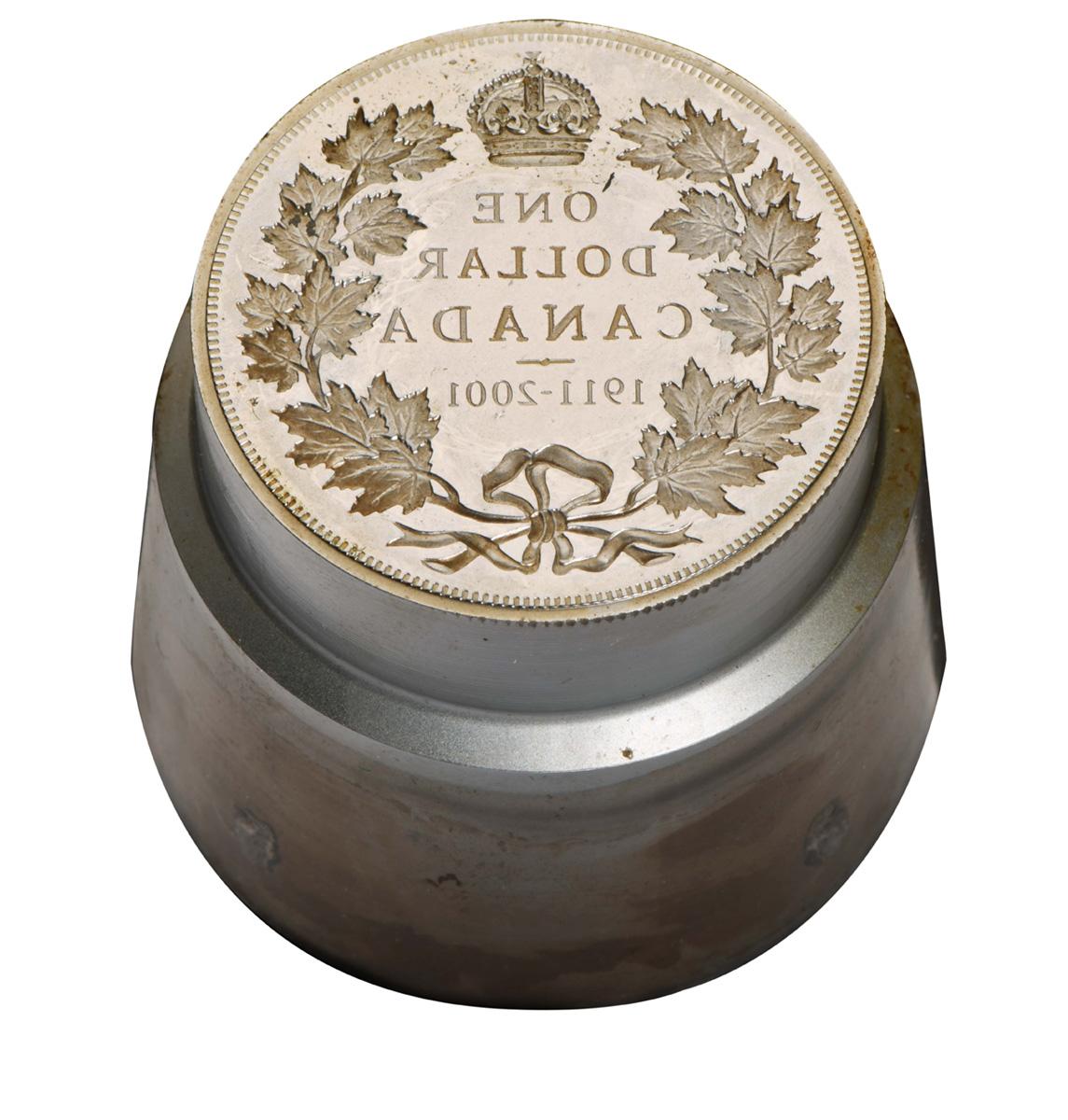 Steel cylinder with a reversed coin design of a wreath of maple leaves and a crown.