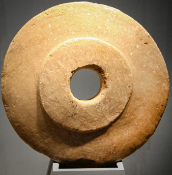 Round stone disc with a round central hole. Flat with raised round section in the centre.